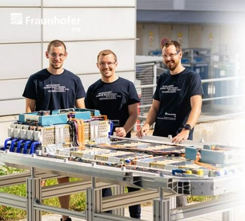 Drei Männer vor einem Tisch mit elektronischen Verbindungen