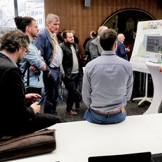 Eine Gruppe von Menschen diskutieren über ein Thema an einem Whiteboard