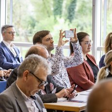 Mehrere Personen aus dem Publikum, ein Mann fotografiert etwas.