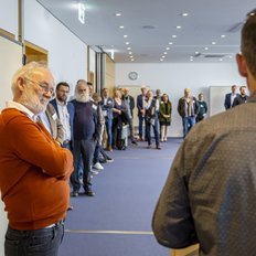 Das Publikum einer Veranstaltung steht in einem Raum.