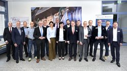Gruppenbild mit Männern im Anzug und Frauen in Blusen